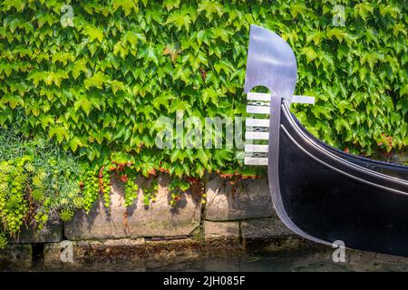 Una gondola ancorata di fronte ad un muro verde a Venezia Foto Stock
