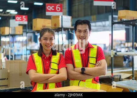 Asian coppia magazzino lavoratore sorridente e braccio trasversale al banco già preparazione contenitore scatola merci consegnato al cliente. Foto Stock