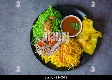 Spaghetti di giada e spaghetti gialli cibo asiatico tailandese, anatra arrosto con spaghetti di giada e gnocchi di maiale sul piatto e salsa d'anatra, spaghetti verdi cinesi Foto Stock