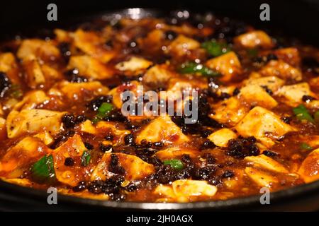 Primo piano estremo Mapo tofu in piastra. Popolare piatto cinese dal Sichuan. Tofu in salsa piccante Foto Stock