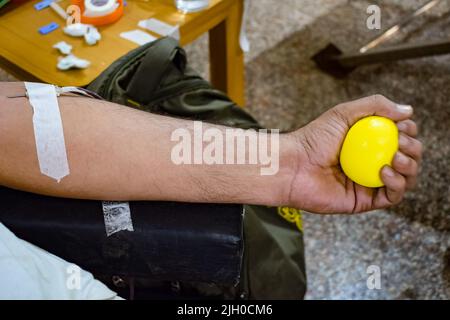 Donatore di sangue al campo di donazione di sangue tenuto con una palla rimbalzante in mano al Tempio Balaji, Vivek Vihar, Delhi, India, Image for World Blood Donor da Foto Stock