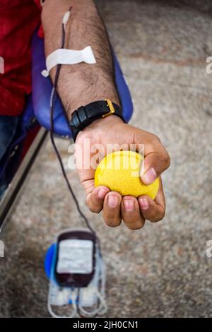 Donatore di sangue al campo di donazione di sangue tenuto con una palla rimbalzante in mano al Tempio Balaji, Vivek Vihar, Delhi, India, Image for World Blood Donor da Foto Stock