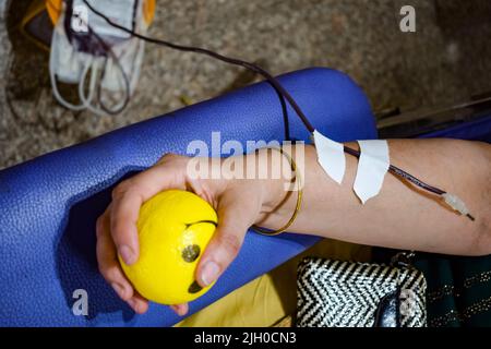 Donatore di sangue al campo di donazione di sangue tenuto con una palla rimbalzante in mano al Tempio Balaji, Vivek Vihar, Delhi, India, Image for World Blood Donor da Foto Stock