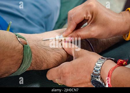 Donatore di sangue al campo di donazione di sangue tenuto con una palla rimbalzante in mano al Tempio Balaji, Vivek Vihar, Delhi, India, Image for World Blood Donor da Foto Stock