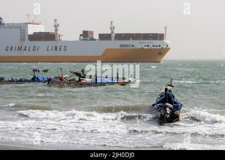 CITTÀ PORTOGHESE, BANJUL, la GAMBIA - 10 FEBBRAIO 2022 la Grande Africa (IMO 9130949) Ro-Ro Cargo nave del Gruppo Grimaldi SPA e barche da pesca locali Foto Stock