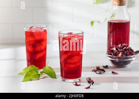 Una bevanda rinfrescante a base di foglie di ibisco essiccato e ghiaccio in un bicchiere. Foto Stock