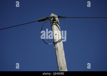 Fili e la parte superiore del vecchio palo di telegrafo di legno più il piccolo cobbweb sul lato destro sotto un cielo di primavera blu, concetto: vintage, uso: Sfondo, carta da parati Foto Stock