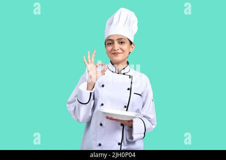 Chef femminile che mostra un segno perfetto per preparare il cibo delizioso per i clienti Foto Stock