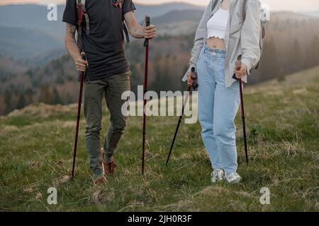 Primo piano di gambe maschili e femminili in scarpe da trekking con bastoncini da trekking nelle mani. Viaggiatori. Foto Stock