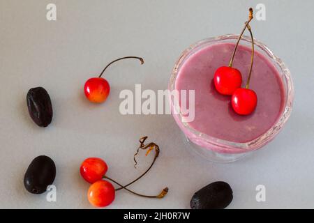 Primo piano, vista dall'alto del souffle Jamun, dessert estivo tradizionale francese preparato con Jamun, condito con ciliegie e isolato su sfondo grigio chiaro. Foto Stock