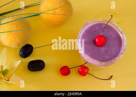 Vista dall'alto, primo piano della mousse di frutta di Jamun o prugna nera, con condimenti di ciliegia. Dessert estivo tradizionale francese isolato su sfondo giallo. Spazio copia. Foto Stock