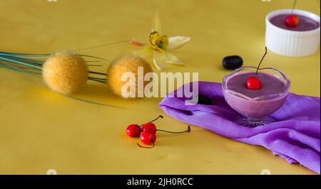 Jamun Mousse, Malabar prugna frutta mousse con guarnizione di ciliegia. Dolce fresco fatto in casa a base di Jamun. Budino estivo su sfondo giallo scuro, primo piano. Foto Stock