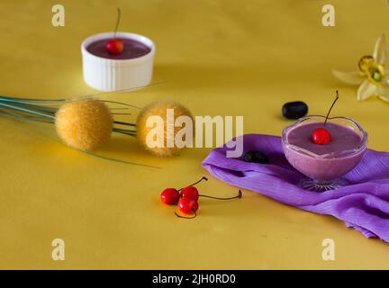 Jamun Mousse, Malabar prugna frutta mousse con guarnizione di ciliegia. Dolce fresco fatto in casa a base di Jamun. Budino estivo su sfondo giallo scuro, primo piano. Foto Stock