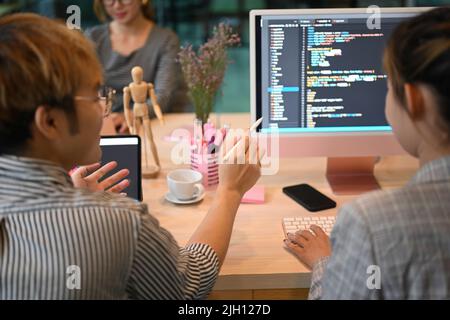 Gli sviluppatori di software asiatici team brainstorming e programmazione su computer desktop in un ufficio moderno Foto Stock