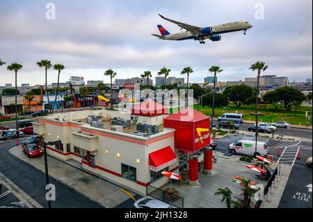 L'aereo Delta Airlines vola sopra il ristorante in-N-out Burger mentre atterra all'aeroporto internazionale di Los Angeles LAX Foto Stock