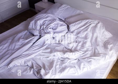 Letto matrimoniale non fatto con biancheria bianca al mattino Foto Stock