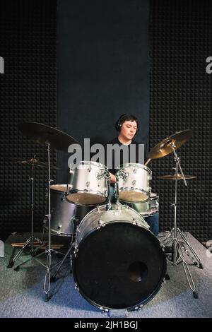 Batterista in cuffie che suona da solo su drum set Foto Stock