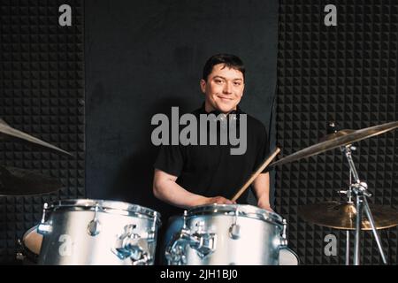 Il batterista sorridente gioca sul drum set Foto Stock