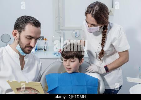 Trattamento ortodontico. Il dentista mostra al ragazzo un esempio di installazione di bretelle sui denti Foto Stock