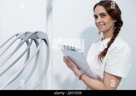 Fidato esperto qualificato felice sorridente medico tenendo appunti con documenti Foto Stock