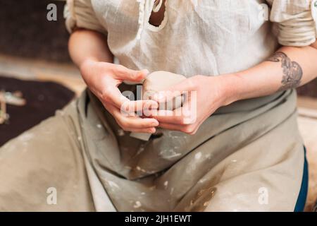 Potter tiene grumo di creta nelle mani. Vista frontale sulle mani dei vasai che tengono grumo di argilla. Processo di lavoro con creta. Foto Stock