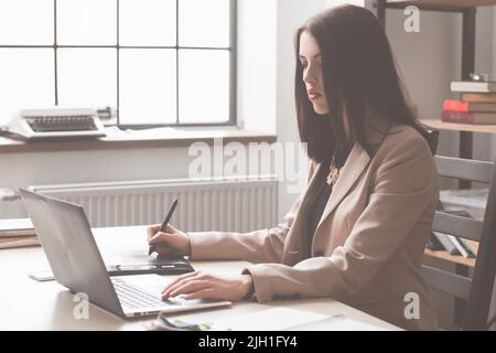 Artista che disegna qualcosa su un tablet grafico in ufficio. Animatore femminile che crea un nuovo personaggio cartoon Foto Stock