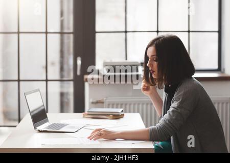 Avvocato o notaio pubblico sul posto di lavoro che lavora con documenti. Consulente legale femminile di successo che legge i file in ufficio Foto Stock