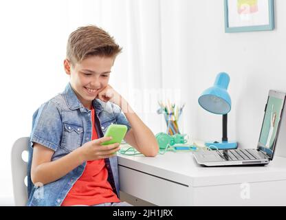 Felice ragazzo con lo smartphone e il computer portatile a casa Foto Stock