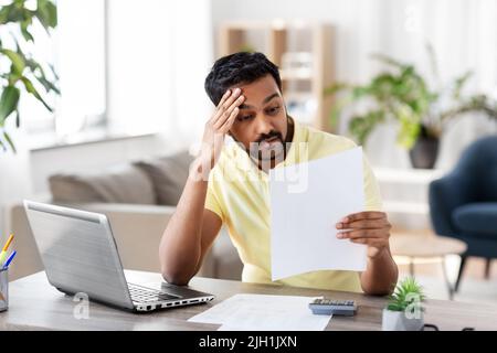 uomo con calcolatrice e documenti che lavorano a casa Foto Stock