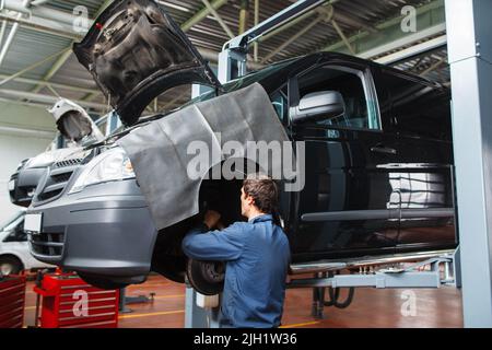 Addetto al controllo dell'impianto frenante in auto presso il garage Foto Stock