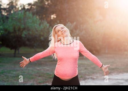 Felice donna incinta godendo il momento, tramonto Foto Stock