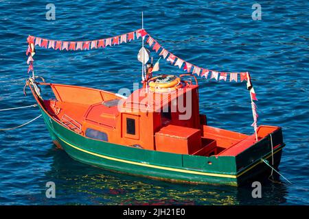 Barca con bandiere colorate nel mare blu a Camara dos Lobos, Isola di Madeira, Portogallo Foto Stock