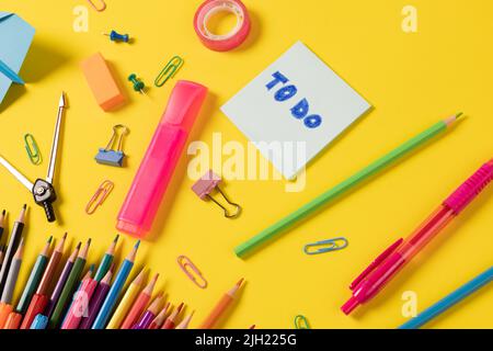 Immaginate di vari articoli per ufficio e utensili di plastica, matite, pastelli su sfondo giallo Foto Stock