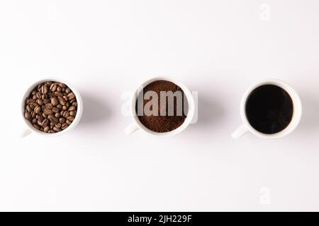 Immagine di tre tazze piene di caffè macinato, chicchi di caffè e caffè su sfondo bianco Foto Stock