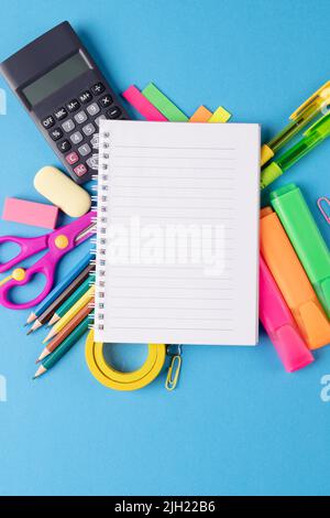 Immagine di vari materiali di consumo per ufficio, penne e notebook su sfondo blu Foto Stock