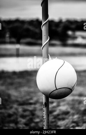 Tetherball seduto inattivo accanto al palo in un cortile. Foto Stock