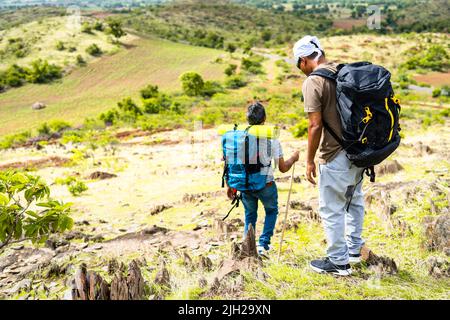 Back view tracking shot di escursionisti di mezza età scendendo dalla cima della collina - concetto di benessere, amicizia e salute mentale Foto Stock