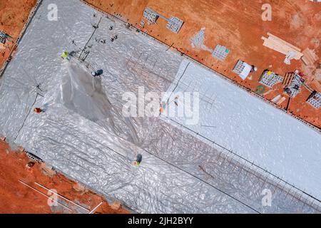 È necessario installare la plastica di barriera prima di versare il calcestruzzo per costruire la fondazione dell'edificio Foto Stock