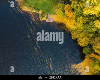 coppia che si posa sul molo al lago coperto con autunno lascia spazio copia Foto Stock