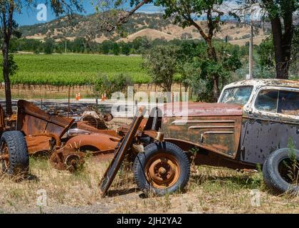 Una vecchia auto arrugginita dell'epoca passata con uno sfondo di vigneto Foto Stock