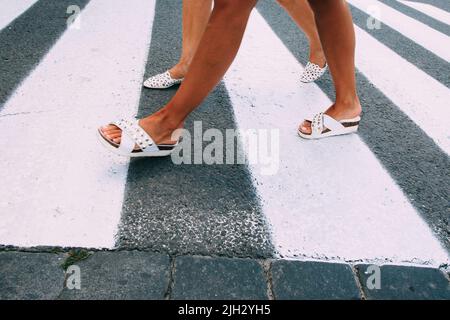 Gambe femminili in scarpe bianche che vanno sulla zebra Foto Stock