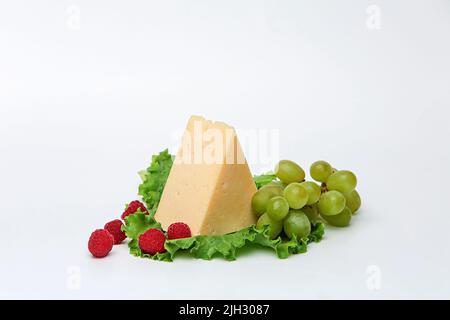 pezzo di formaggio con mele e pomodori su un asse di legno su un bel sfondo Foto Stock