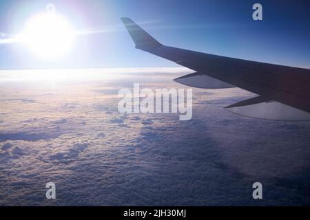 Airbus A220-300 ali in luci al tramonto che volano sopra le nuvole da qualche parte sopra la regione del Mar Baltico in Europa Foto Stock