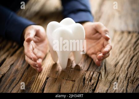 Mano d'uomo proteggere igienicamente sano Dente Bianco sul tavolo riflettente Foto Stock