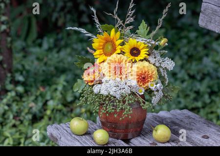 bouquet di dahlias d'arancia e girasoli in tazza di birra di legno Foto Stock