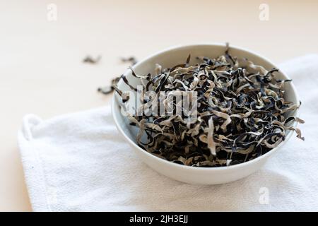 Funghi mun secchi, medicina tradizionale cinese e cucina. Funghi ingredienti in piatto su sfondo beige Foto Stock