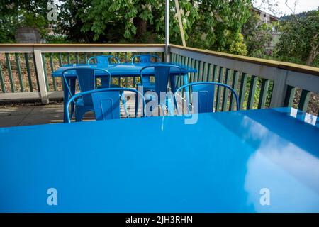 Vista colorata di sedie blu brillante radunate intorno ad un tavolo blu su un patio esterno in un ristorante Foto Stock