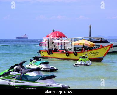 Gli uomini gestiscono barche turistiche in mare sull'isola di Koh Larn, che può essere spelt Ko Larn o Ko Laan o Ko LAN, Thailandia, Asia. Jetskis sono in primo piano. Foto Stock