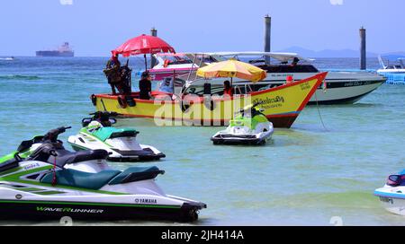 Gli uomini gestiscono barche turistiche in mare sull'isola di Koh Larn, che può essere spelt Ko Larn o Ko Laan o Ko LAN, Thailandia, Asia. Jetskis sono in primo piano. Foto Stock