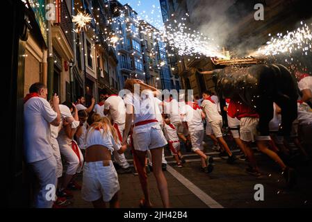 Pamplona, Spagna. 14th luglio 2022. La gente corre dietro il toro del fuoco durante le festività di San Fermín. Un uomo che porta una struttura a forma di toro carica di fuochi d'artificio chiamati Toro de Fuego (toro del fuoco), spara fuoco e corre per le strade della città vecchia di Pamplona durante le festività di San Fermín. (Foto di Elsa A Bravo/SOPA Images/Sipa USA) Credit: Sipa USA/Alamy Live News Foto Stock